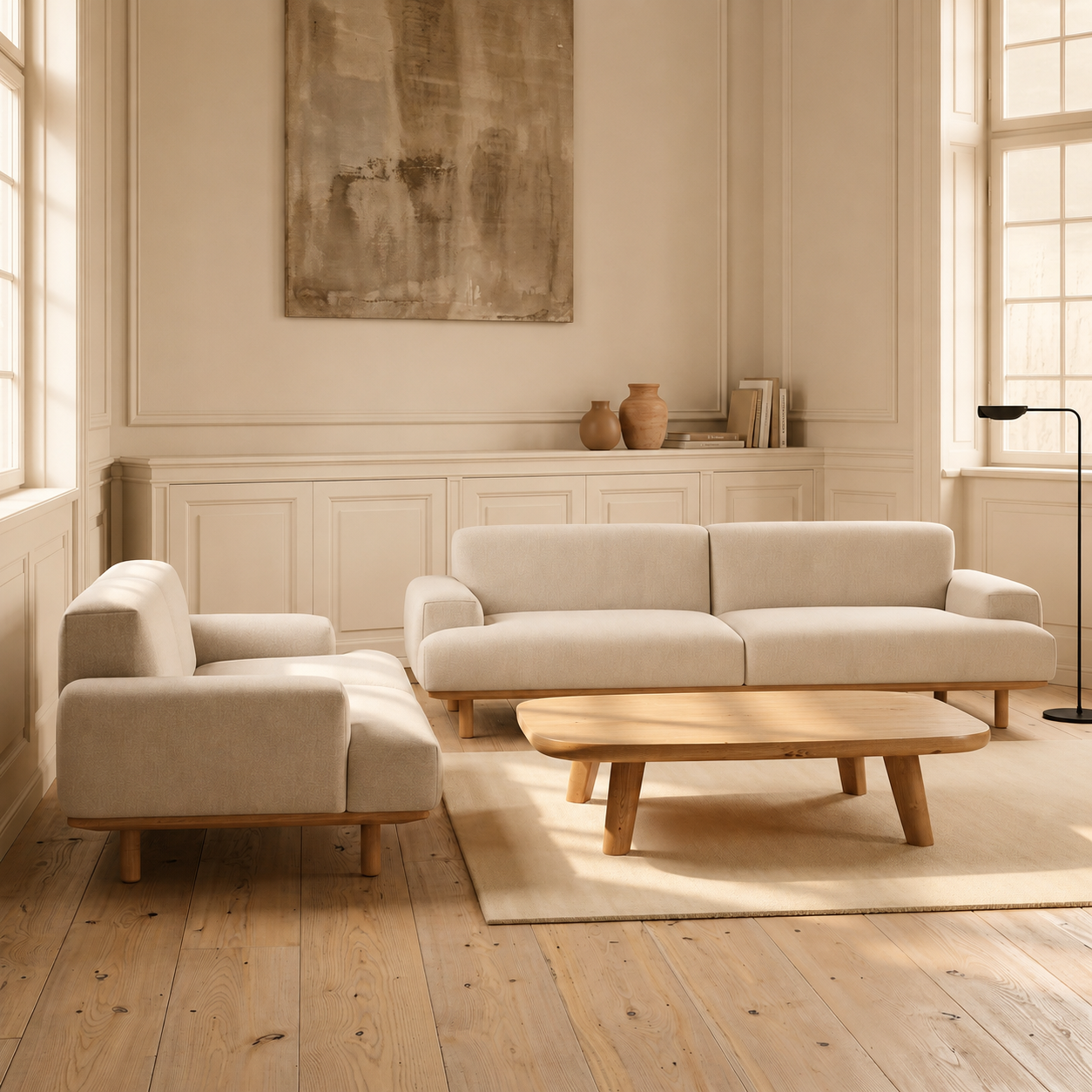 Beige sofa and armchair in a room with wooden floor and large windows.